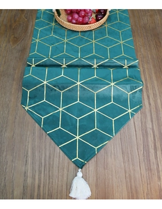 Close-up of velvet table runner with gold geometric lines and a white tassel detail