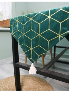 Detail of dark green velvet table runner with gold geometric patterns and tassels