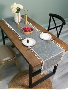 Detail of dark grey velvet table runner with gold geometric lines and white tassels
