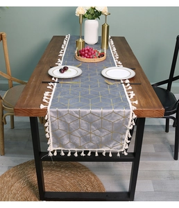 Close-up of velvet table runner featuring gold geometric patterns and white tassels