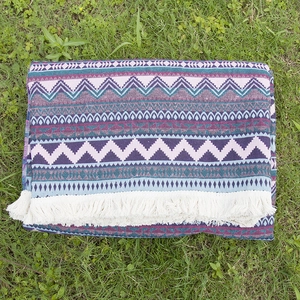 Bohemian geometric woven picnic mat with white tassels on grass for outdoor camping