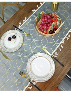 Macro detail of Nordic velvet runner with gold geometric patterns and white tassels
