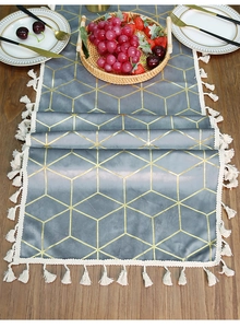 Close-up of luxury grey velvet table runner with gold geometric lines and white tassels