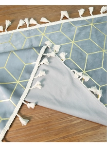 Close-up of grey velvet table runner featuring gold geometric patterns and white tassels