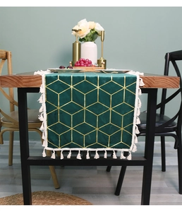 Close-up of dark green velvet table runner with gold geometric patterns and white tassels