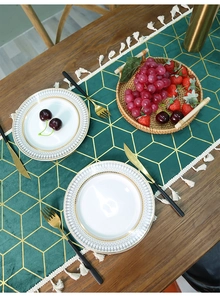 Detail of dark green velvet table runner with gold geometric lines and white tassels