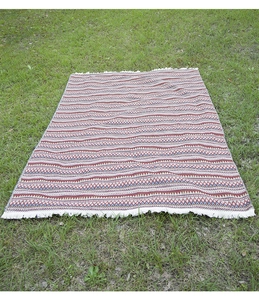 Detail of bohemian outdoor picnic blanket with geometric patterns and white tassels