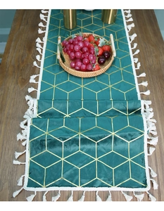 Close-up of dark green velvet table runner with gold geometric honeycomb pattern and tassels