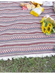 Detail of bohemian picnic blanket with geometric patterns and white woven fringe trim
