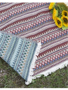 Detail of bohemian picnic blanket with colorful geometric weave and white fringe tassels