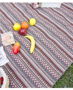 Detail of bohemian picnic mat with geometric weave pattern on green grass