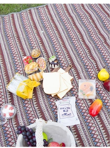 Bohemian geometric picnic blanket with vibrant ethnic patterns on green grass for camping