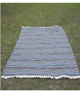 Close-up of Bohemian picnic blanket featuring woven geometric patterns and white tassels