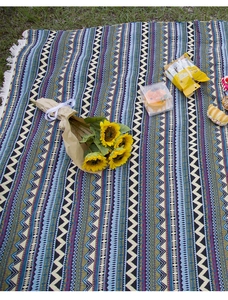 Close-up of bohemian picnic blanket with geometric patterns and fringe on lawn