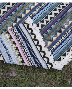 Detailed view of bohemian woven picnic blanket with colorful geometric patterns and white tassels