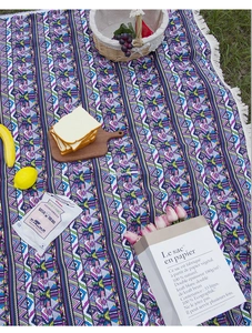Detail of bohemian outdoor picnic mat with colorful geometric weave and white fringe tassels