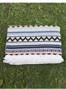 Detail view of bohemian outdoor picnic blanket with fringe and colorful geometric patterns