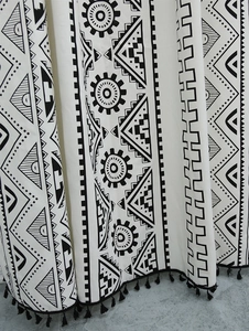 Detail of bohemian geometric print curtain fabric with black tassel fringe trim