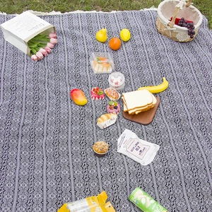 Bohemian style woven picnic mat with black and white geometric patterns and tassel edges