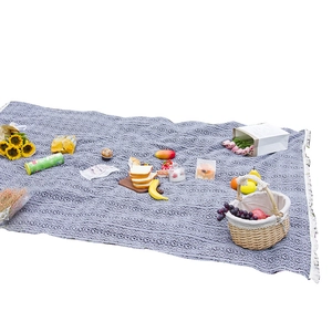 Bohemian picnic blanket with blue and white geometric patterns and tassel edges outdoors