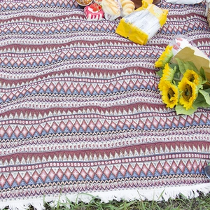 Bohemian style outdoor picnic blanket with geometric patterns and tassels on green grass