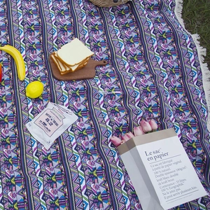 Bohemian geometric picnic blanket with white fringe tassels on grass for camping