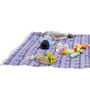 Bohemian woven picnic blanket with geometric patterns and decorative white tassels