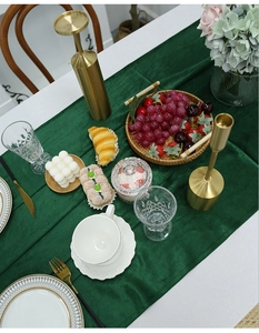 Deep green velvet table runner with gold accents for elegant holiday party dining decor