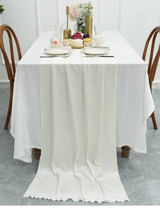 Detail view of ivory velvet table runner with elegant wavy edges on a luxury dining table