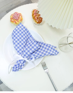 Blue and white plaid linen napkin with white silk ribbon bow on a ceramic plate