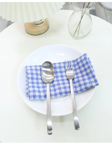Detailed macro view of matte stainless steel cutlery set on blue checkered napkin