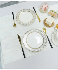 Close-up of white velvet table runner with gold-rimmed plates and elegant dinnerware