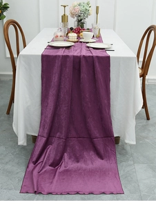 Close-up of luxury purple velvet table runner with decorative scalloped edges on white linen