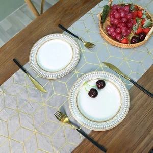 Chemin de table nordique en velours gris avec motifs géométriques dorés sur table