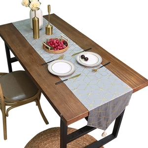 Chemin de table en velours bleu clair avec motifs géométriques dorés et des glands