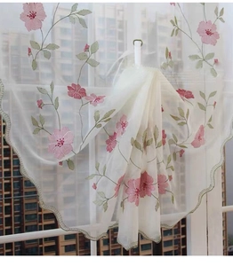 Détail de broderie marguerite et bordure ondulée verte sur rideau voilage beige