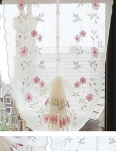 Détail de fleurs de cerisier brodées sur un voilage blanc transparent avec bordure festonnée