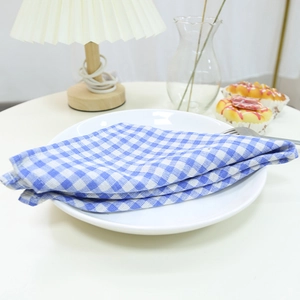 Blue and white checkered cotton linen placemat folded on a ceramic plate