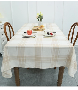 Detail of beige and white checkered linen tablecloth draped over a dining table