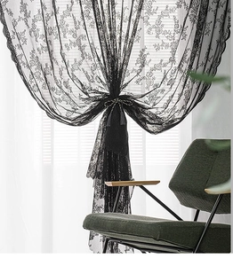 Detailed texture of black lace curtain with retro floral embroidery and tassel tieback