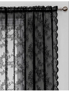 Detail of black lace curtain with floral patterns and wavy edges on a metal rod