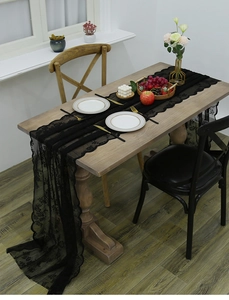 Detail showing the intricate floral lace texture and scalloped edges of a black table runner