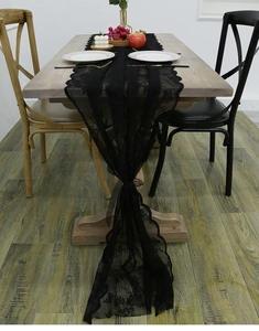 Detail of black lace table runner with hollow floral pattern and scalloped edges