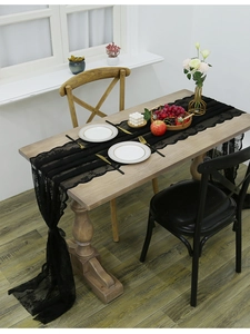 Detail showing elegant black lace table runner with scalloped edges on a wooden dining table