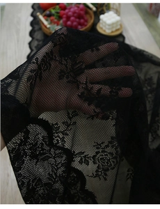 Detailed view of sheer black lace table runner with floral embroidery and scalloped edges