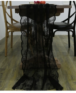 Macro detail of black lace table runner with floral rose embroidery and scalloped edges