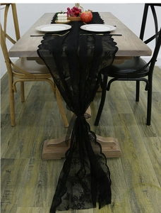 Detail of black lace table runner featuring floral embroidery and elegant scalloped edges