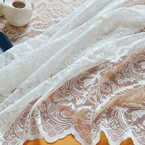 Nappe élégante en dentelle blanche à motifs floraux sur une table en bois rustique