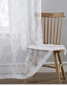 Détail du rideau en dentelle blanche avec broderie florale complexe sur le tissu en mesh