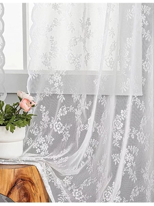 Gros plan du rideau en dentelle blanche avec motifs floraux et bords festonnés